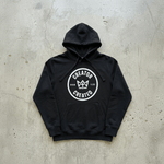 Black Foundation Hoodie with minimalist logo on concrete surface