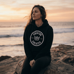 Black Foundation Hoodie with minimalist logo on concrete surface